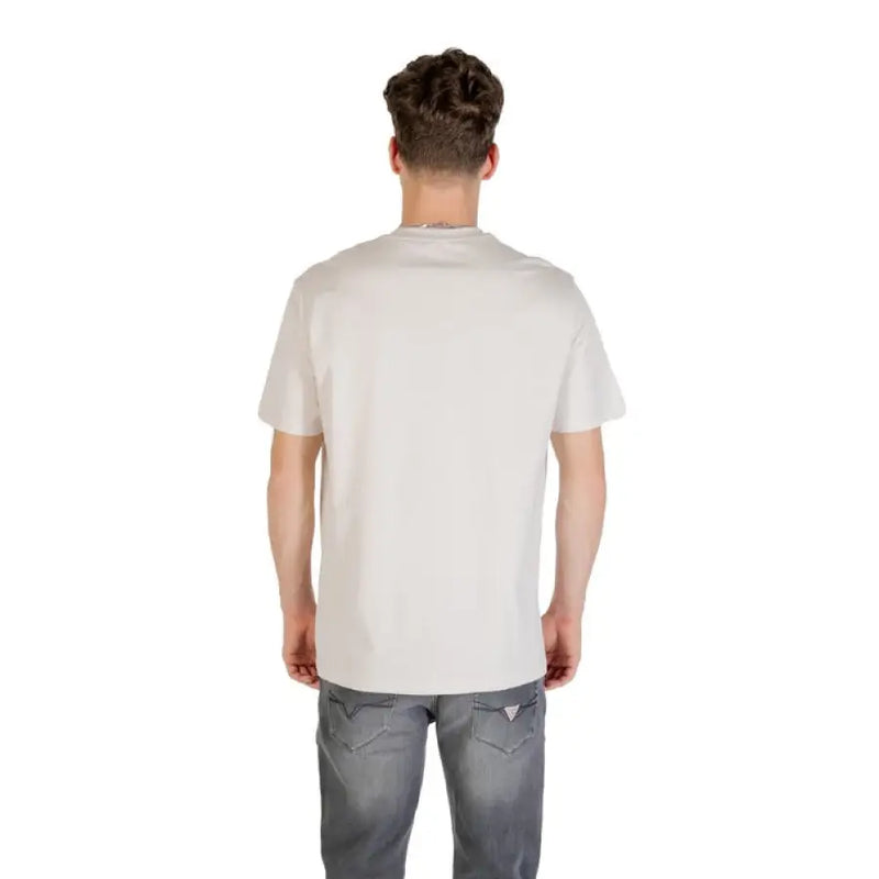 Man wearing a light-colored T shirt with black logo and gray jeans displayed in product listing