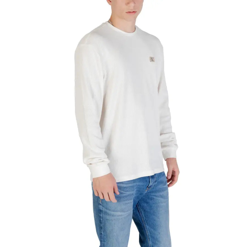 Man wearing a long-sleeved white shirt and blue jeans posing confidently