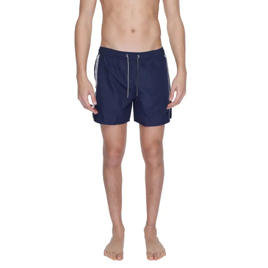 
                      
                        Emporio Armani Underwear Swimwear - man in navy swimsuit with white shirt and black shorts
                      
                    