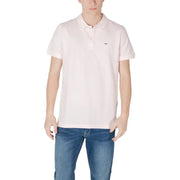 Man wearing pink polo shirt and blue jeans for Tommy Hilfiger Men’s Summer Green Underwear display