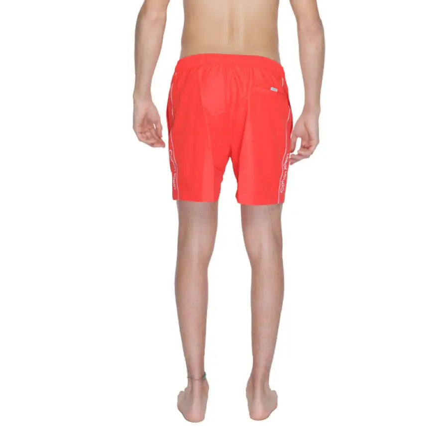 
                      
                        Calvin Klein man in red swim trunks with white logo - Calvin Klein Men Swimwear
                      
                    