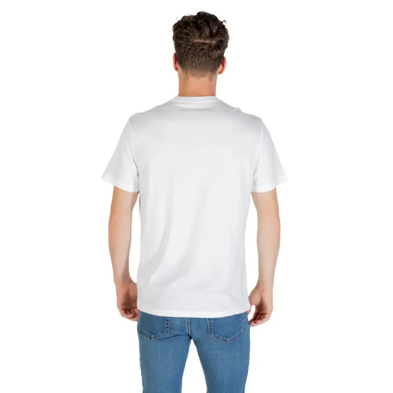 Man wearing Calvin Klein White T Shirt and blue jeans standing against a neutral background