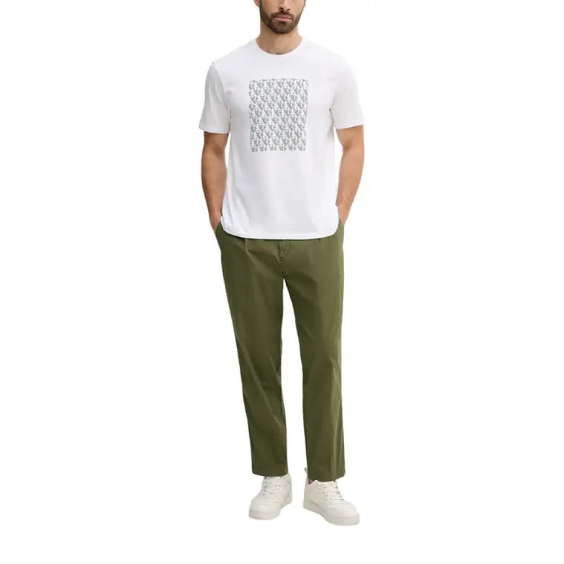 Man wearing white short sleeve T shirt with gray pattern and green pants