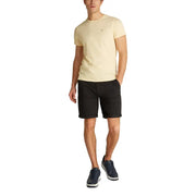 Man in a yellow T-shirt and black chino shorts modeling the men’s casual outfit