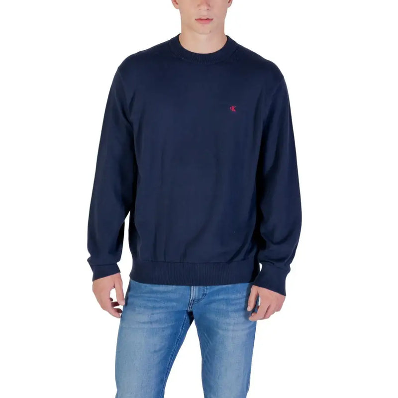 Men’s navy blue long-sleeved crewneck sweatshirt with red logo paired with light wash jeans