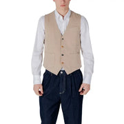 Man wearing a beige vest and blue pants styled with a navy vest and white shirt