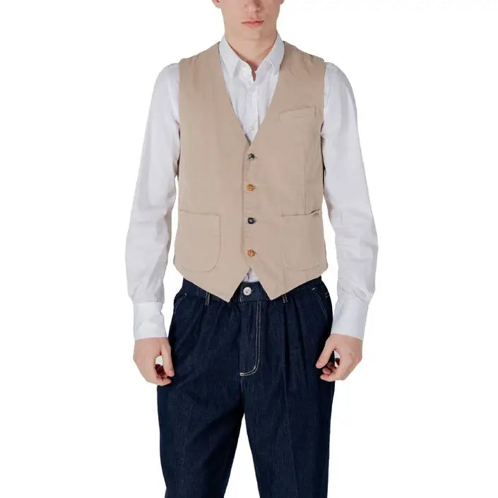Man wearing a beige vest and blue pants styled with a navy vest and white shirt