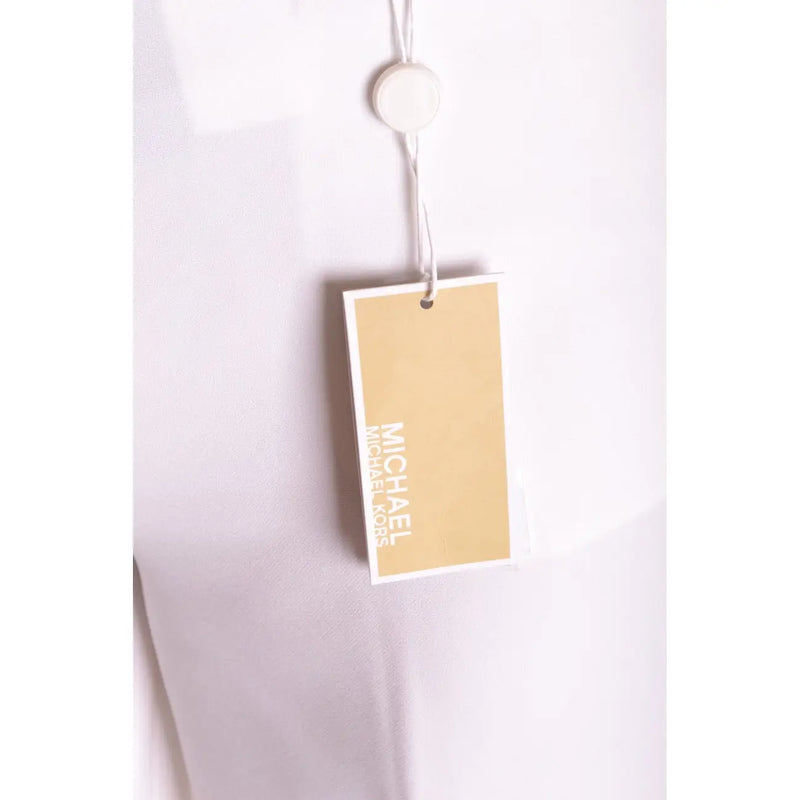 Eine beige Michael Kors Markenetikett mit weißer Schrift ist an einer weißen Stretch-Damenhose mit Reißverschluss und Knöpfen befestigt.