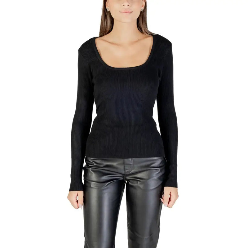 Woman wearing Morgan De Toi black long knit sweater with square neckline and leather-look pants