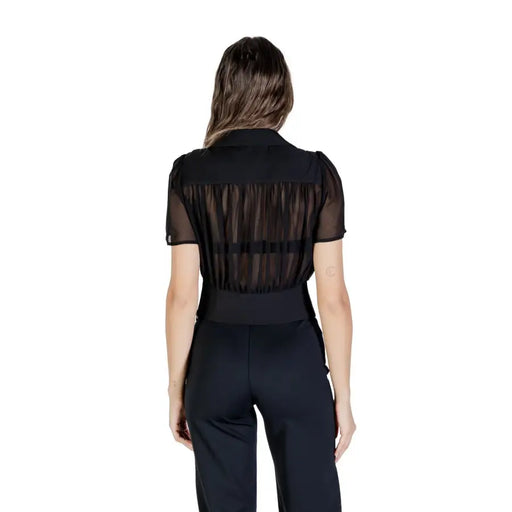 Women wearing Morgan De Toi black V neck blouse with sheer stripes and high-waisted wide-leg pants