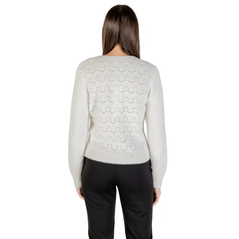 Woman wearing a light grey patterned knit sweater and black pants, showcasing Morgan De Toi cardigan
