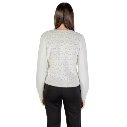 Woman wearing a light grey patterned knit sweater and black pants, showcasing Morgan De Toi cardigan