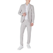 Mulish Grauer Herrenanzug in schmaler Passform aus Polyester-Viskose-Mischgewebe, getragen über einem weißen Hemd mit weißen Sneakers.