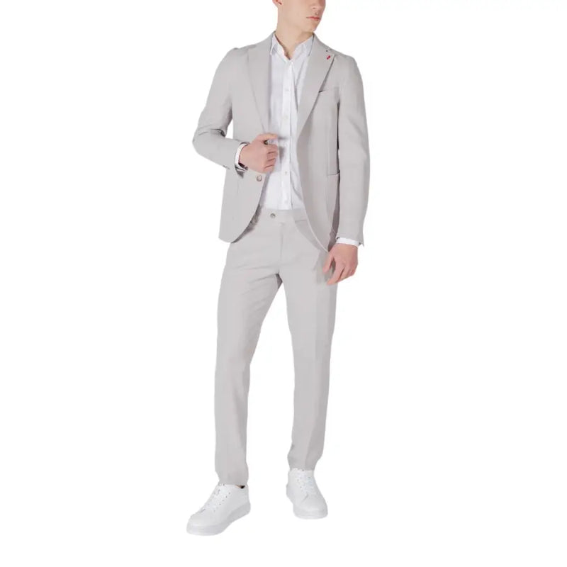 Mulish Grauer Herrenanzug in schmaler Passform aus Polyester-Viskose-Mischgewebe, getragen über einem weißen Hemd mit weißen Sneakers.