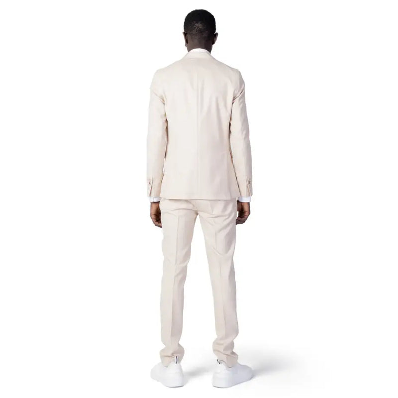 A man wearing a cream-colored Mulish men suit made of beige polyester viscose blend with matching trousers and white sneakers