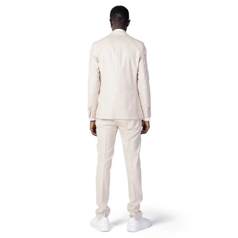 A man wearing a cream-colored Mulish men suit made of beige polyester viscose blend with matching trousers and white sneakers