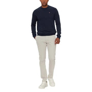 Navy blue crew neck sweater with white logo and light gray pants
