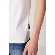 Weiß t-shirt mit goldenem Logo und Taschenverzierung.