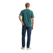 Ein Mann, der einen new balance Grünes Herren-T-Shirt aus Baumwolle mit kurzen Ärmeln und Rundhalsausschnitt in Türkis, kombiniert mit dunkelblauen Jeans
