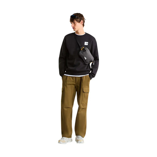 Schwarze The North Face Umhängetasche mit gelbem Reißverschlussanhänger und weißem Logo-Patch, kombiniert mit einem schwarzen Herren-Baumwoll-Sweatshirt