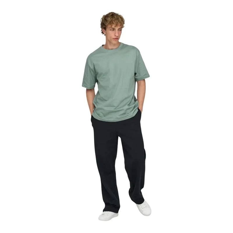 Ein Mann, der einen Only grünes Baumwoll-T-Shirt von and Sons für Herren, lockere Passform, mit einem weichen, gedeckten salbeigrünen Rundhalsausschnitt