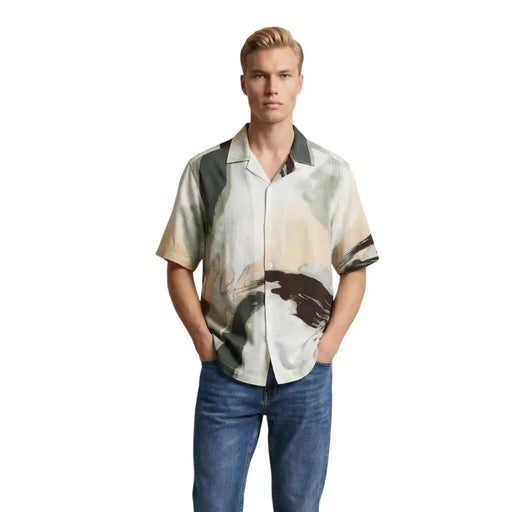 A man wearing an Only & Sons short-sleeved button-up shirt with an abstract earth tone painterly design