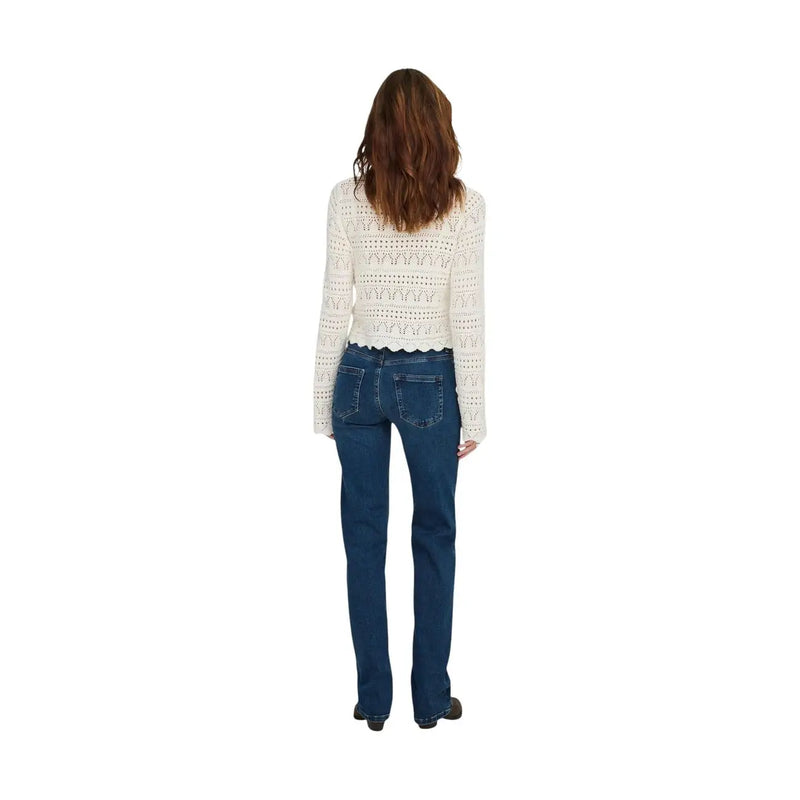 Eine Frau, die only Damen-Jeans aus blauem, mittellangem, geradem Baumwoll-Denim, kombiniert mit einer cremefarbenen Häkelspitze top