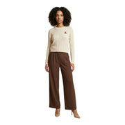 Cremefarbener Zopfstrickpullover mit kleinem, gesticktem Logo, kombiniert mit einer braunen, schmal geschnittenen Hose aus Polyester-Elastan.