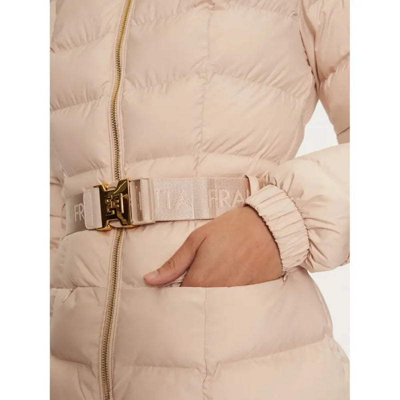 Close-up of a person wearing a belted light pink puffer jacket with gold buckle and ribbed cuffs