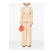 A vibrant orange fabric clutch with a structured design paired with a pinko yellow linen blazer with button front and pockets