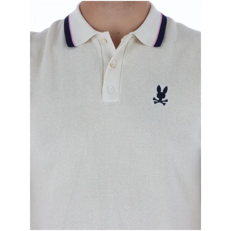 Cremefarbenes Herren-Poloshirt aus Baumwolle mit Psycho-Bunny-Motiv, marineblau-rosa Kragenbesatz und schwarzem, gesticktem Logo (kurze Ärmel).