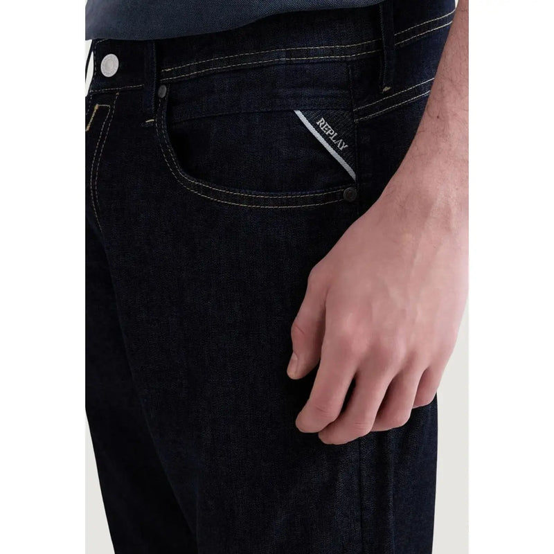 Back side of dark blue denim Replay men jeans with white stitching and a brand label on the back pocket