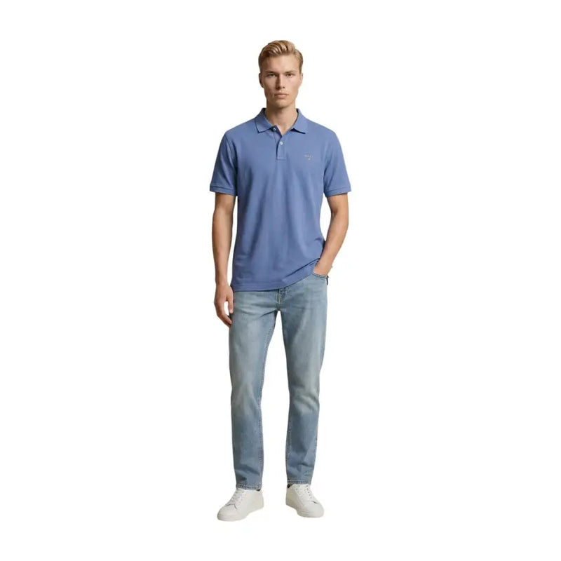 Ein Mann trägt ein hellblaues, kurzärmeliges Poloshirt und dazu eine hellblaue, normal geschnittene Slim-Fit-Jeans aus Baumwollstretch von Replay.