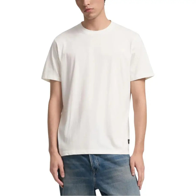Wiederholungsmänner t-shirt minimalistischer, cremefarbener Rundhalspullover aus Baumwolle mit dezentem schwarzem Markenetikett am unteren Saum.