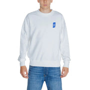 Men’s white crewneck sweatshirt with blue graphic on chest paired with blue jeans