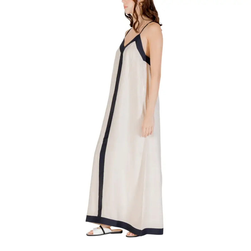 A flowing off-white sleeveless floor length maxi dress with black trim on straps front seam and hemline