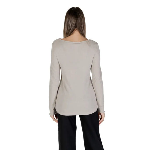 Women wearing beige long-sleeve boat neck knit sweater with black trousers for a stylish look