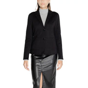 Women wearing black tailored blazer with flap pockets over light grey turtleneck and black faux leather midi skirt