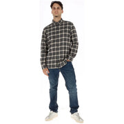 Ein Mann, der einen Timberland Schwarzes Herrenhemd aus karierter Baumwolle in Schwarz-Weiß, kombiniert mit dunkelblauen Jeans