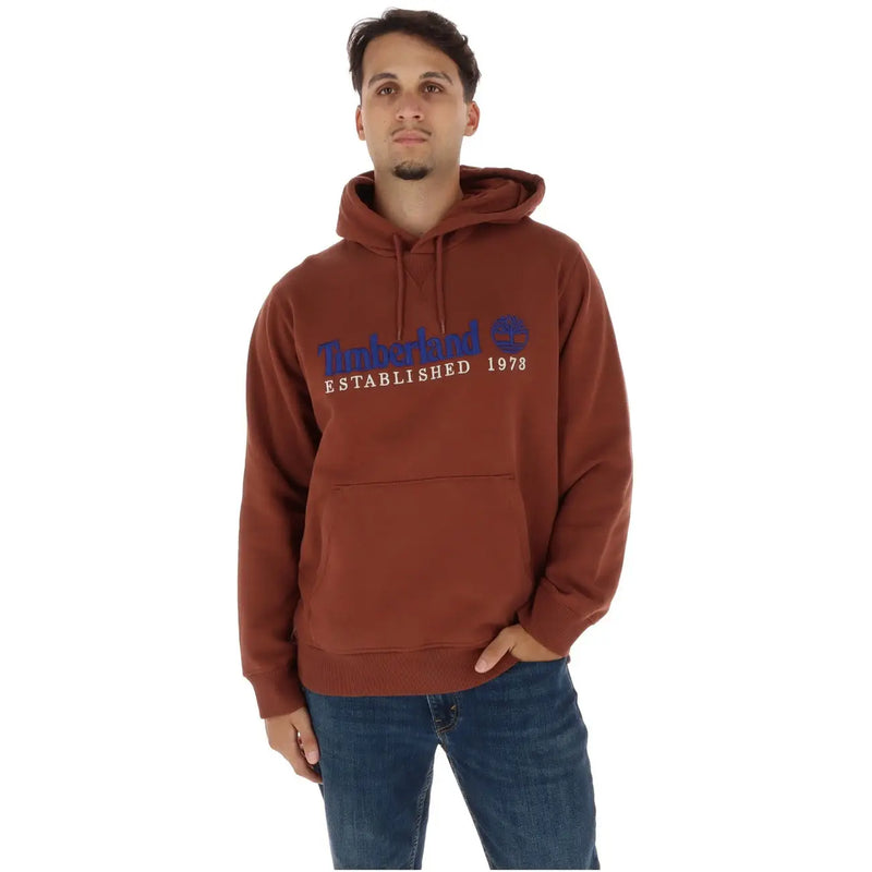 Braun Timberland Hoodie mit blau-weißem Logo-Schriftzug auf der Brust, kombiniert mit grauen Fleece-Taschen aus Baumwoll-Sweatshirt.