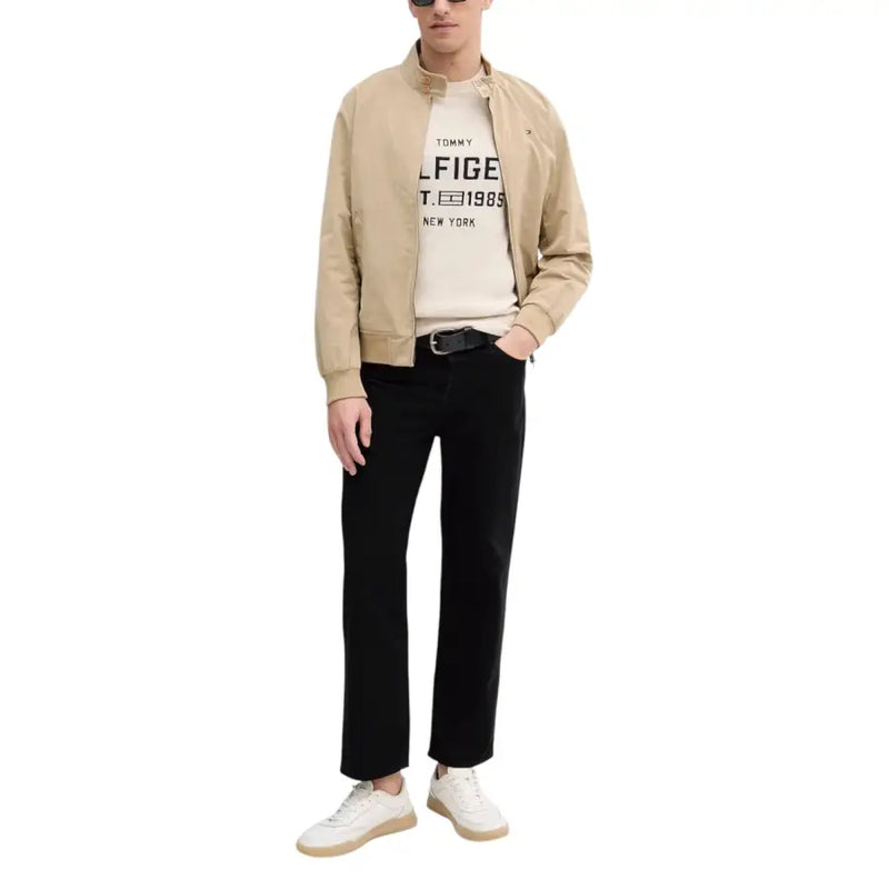 Beige tommy hilfiger bomber jacket with black pants and white sneakers.