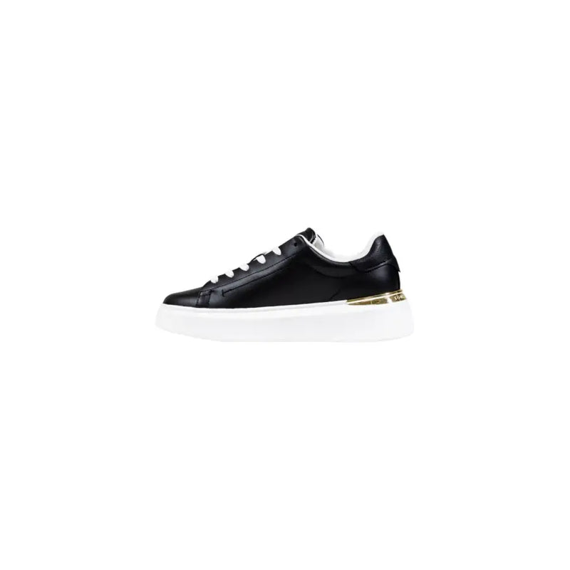 Black leather sneaker with gold accents and white laces.