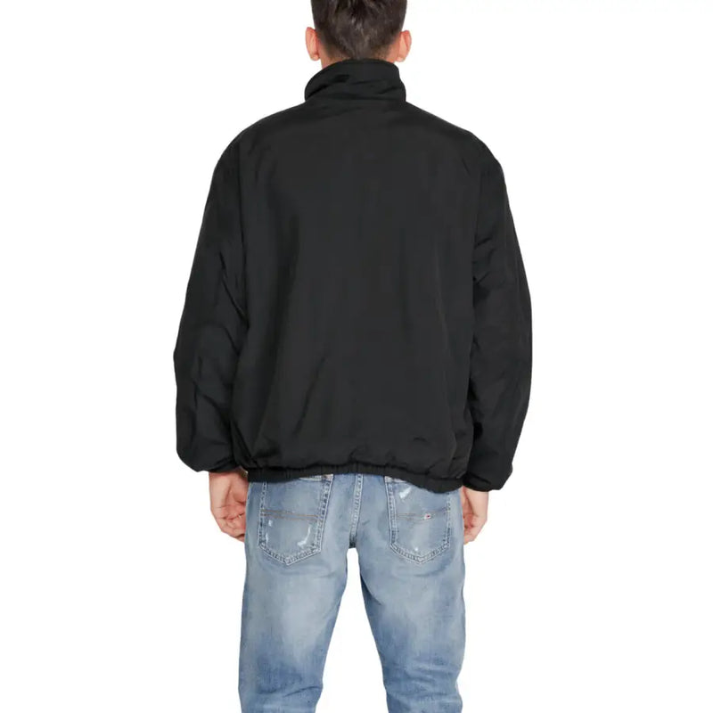 Black long-sleeved puffer jacket with high collar and elastic hem over distressed jeans