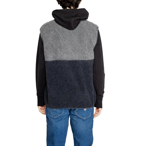 Tommy Hilfiger two-tone fleece vest with gray diamond pattern upper and navy lower section worn over black sleeves