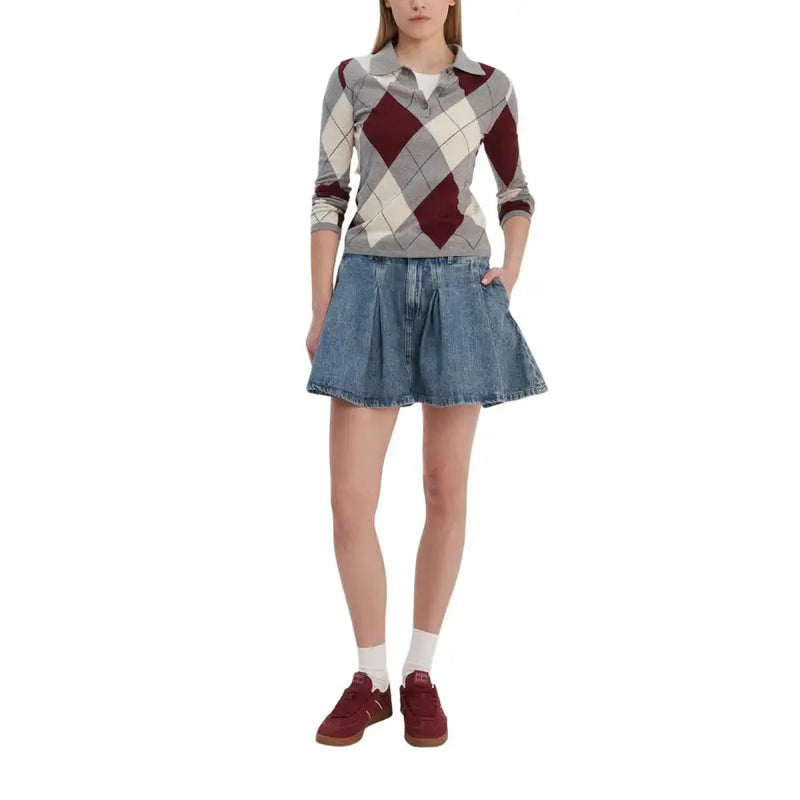 A woman wears a long-sleeved argyle polo shirt with maroon gray and cream over a white undershirt with a Tommy Hilfiger blue organic cotton denim skirt