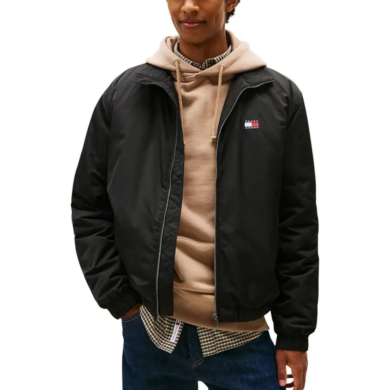 Schwarze Tommy Hilfiger Bomberjacke aus Polyester mit Reißverschluss und kleinem rot-weiß-blauem Flaggenlogo auf der linken Brust.