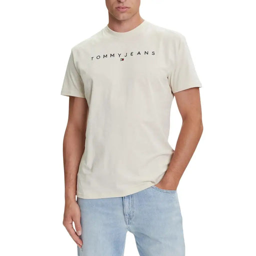 Beige tommy hilfiger jeans men’s t-shirt with black logo and red flag emblem across the chest