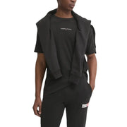 Schwarzer Tommy Hilfiger Jeans-Hoodie über passendem schwarzem T-Shirt und Hose mit dezentem weißen Brustlogo.