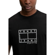 Schwarz Tommy Hilfiger Herrenjeans t-shirt mit weißem Tommy Jeans NYC 1985 Logo im Kreidestil auf der Vorderseite