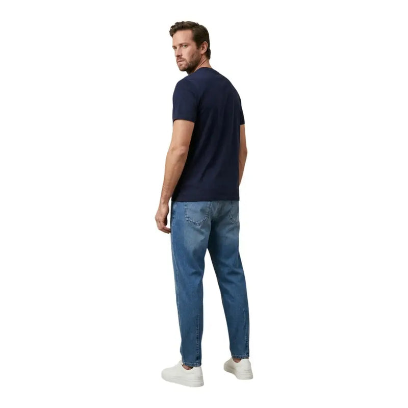Ein Mann, der ein dunkelblaues, kurzärmeliges Tommy Hilfiger-Hemd trägt. t-shirt und mittelblaue Jeans für Herren